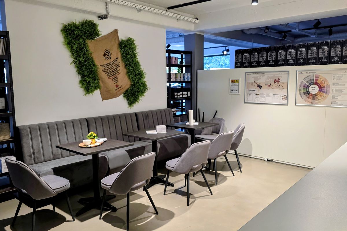 Schulungsraum der Coffee Academy von rhiinland.com mit Sitzbank, Tischen und Aromarad an der Wand