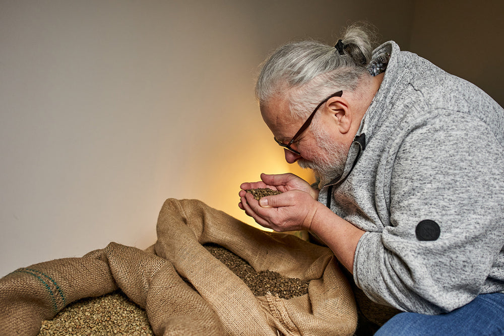 Detlef Klees riecht an Rohkaffeebohnen aus einem Jutesack