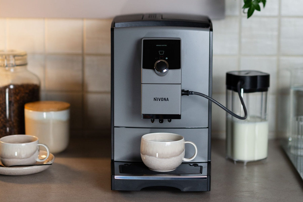Nivona NICR 793 mit angeschlossenem Milchbehälter und Tasse auf der Arbeitsplatte