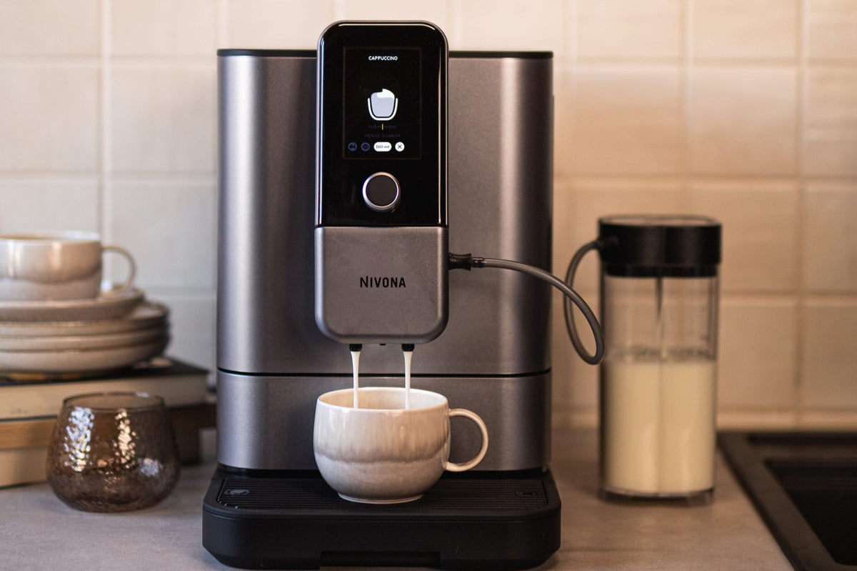 NIVONA NIVO 8'103 bereitet einen Cappuccino zu, das Display zeigt Menge und Schaummenge, daneben der Milchbehälter