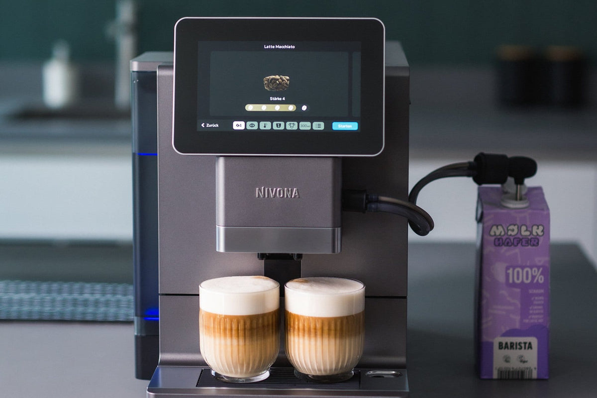 NIVONA Kaffeevollautomat bereitet zwei Latte Macchiato mit Hafermilch zu, das Display zeigt Stärke 4